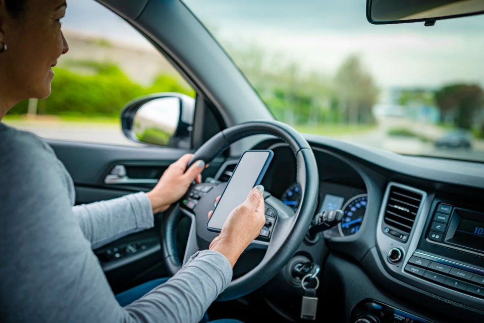 a woman is driving a car and looking at her phone