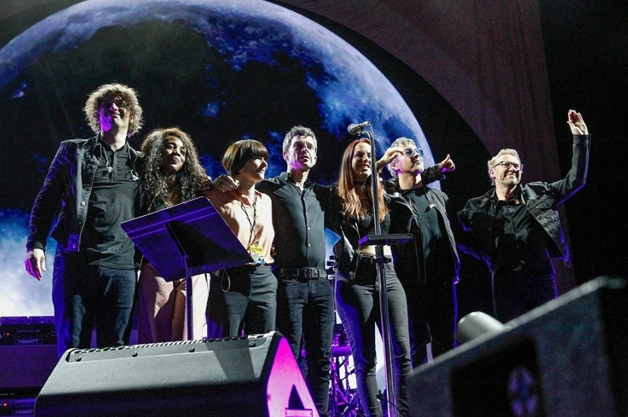 a group of people standing on a stage with a moon in the background