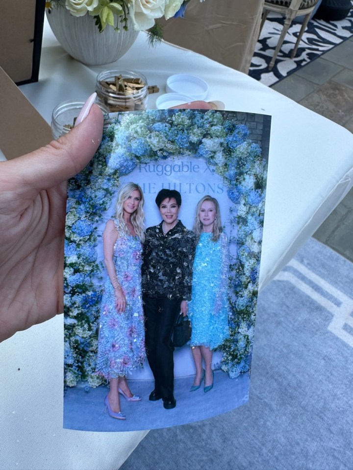 a woman holds a picture of three women in front of a sign that says ruggeable