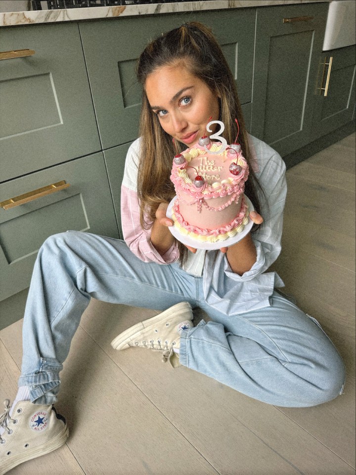 a woman sitting on the floor holding a cake with the number 3 on it