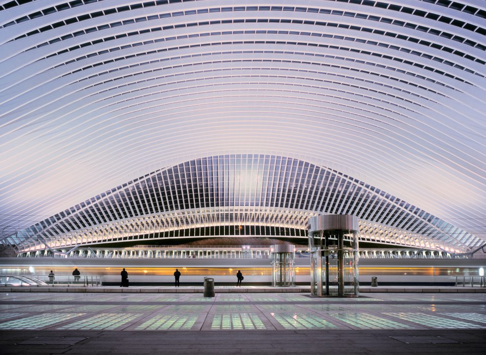 a large building with a curved ceiling and a train in the background