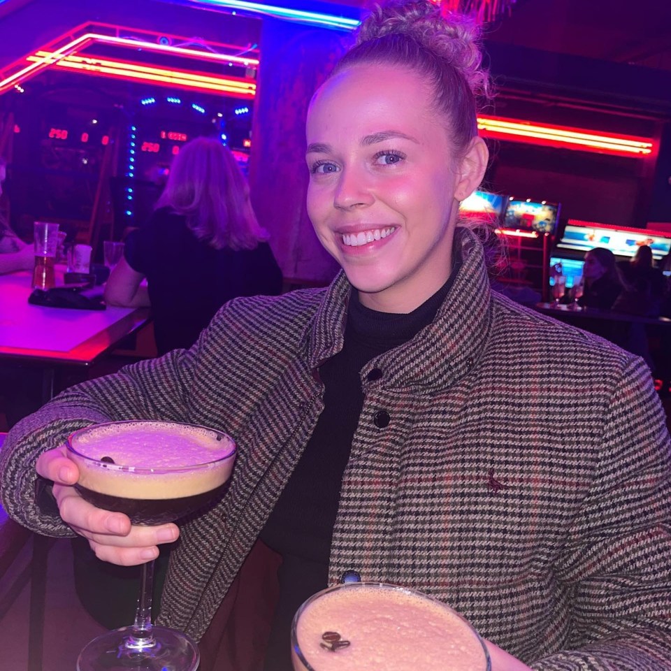 a woman in a plaid jacket holds a martini in her hand