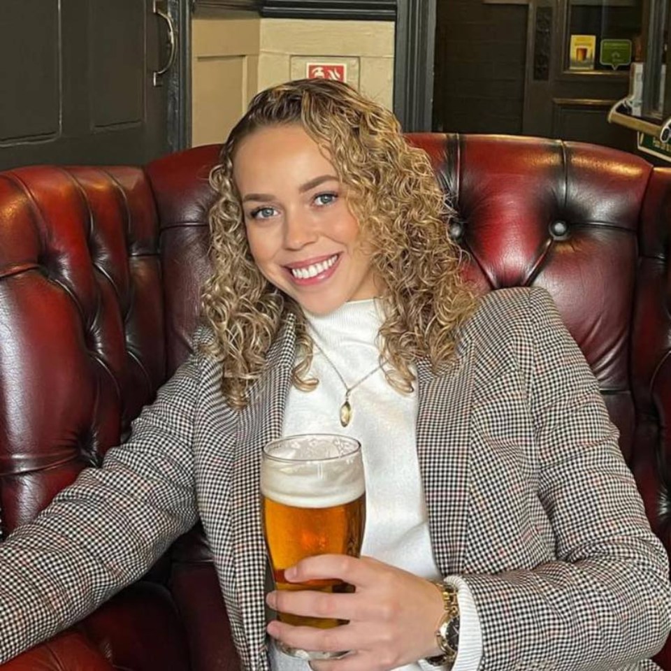 a woman is sitting in a chair holding a glass of beer