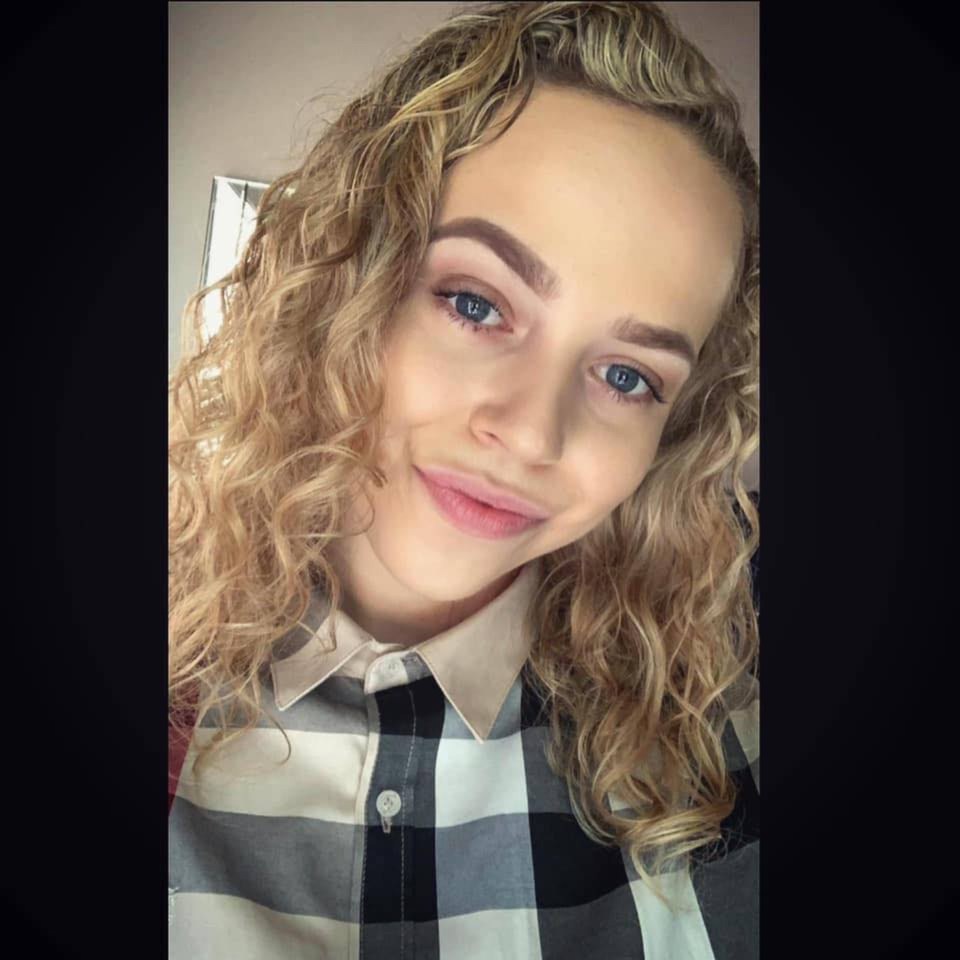 a woman with curly hair is wearing a plaid shirt