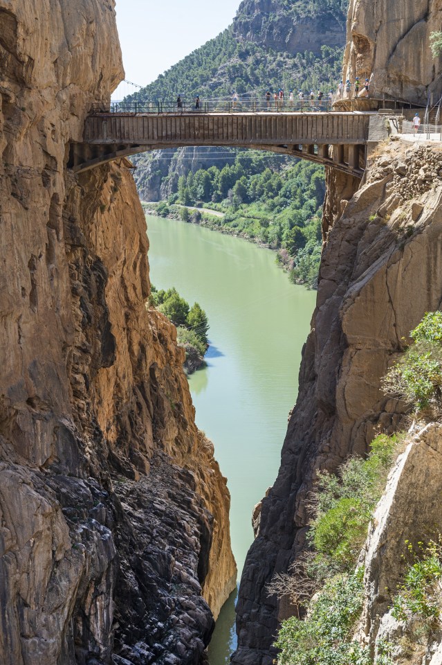 a bridge over a river between two rocky cliffs