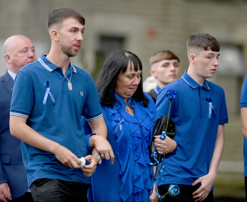 a group of people wearing blue shirts with ribbons on them