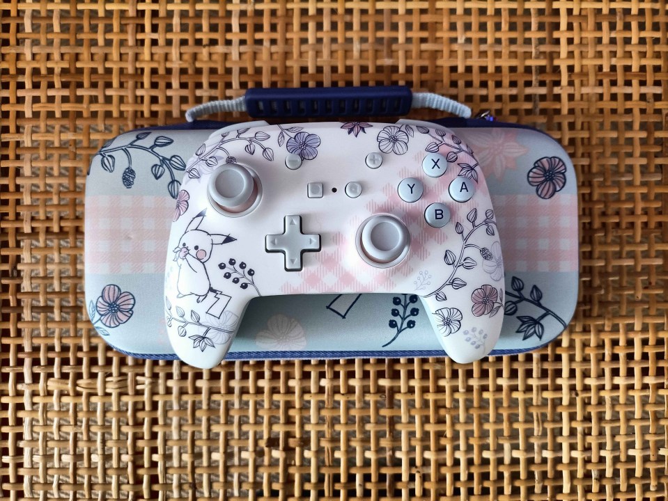 a nintendo switch controller sits on top of a floral case