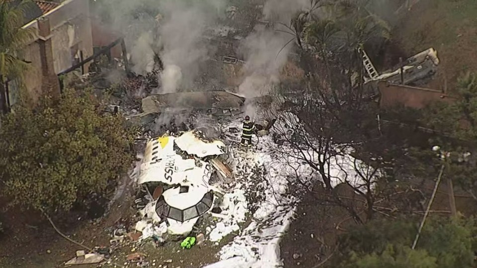 an aerial view of a plane wreckage with smoke coming out of it