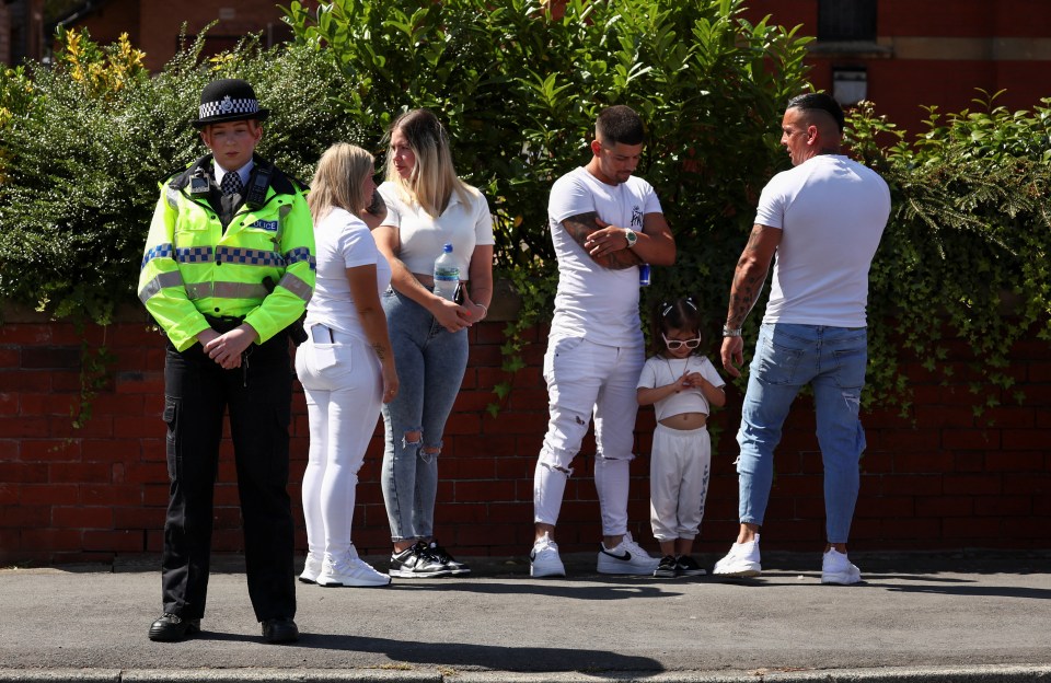 A police officer guards St Patrick’s Catholic Church as people stand outside