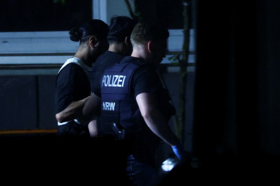 a man in a polizei vest is being escorted by another man