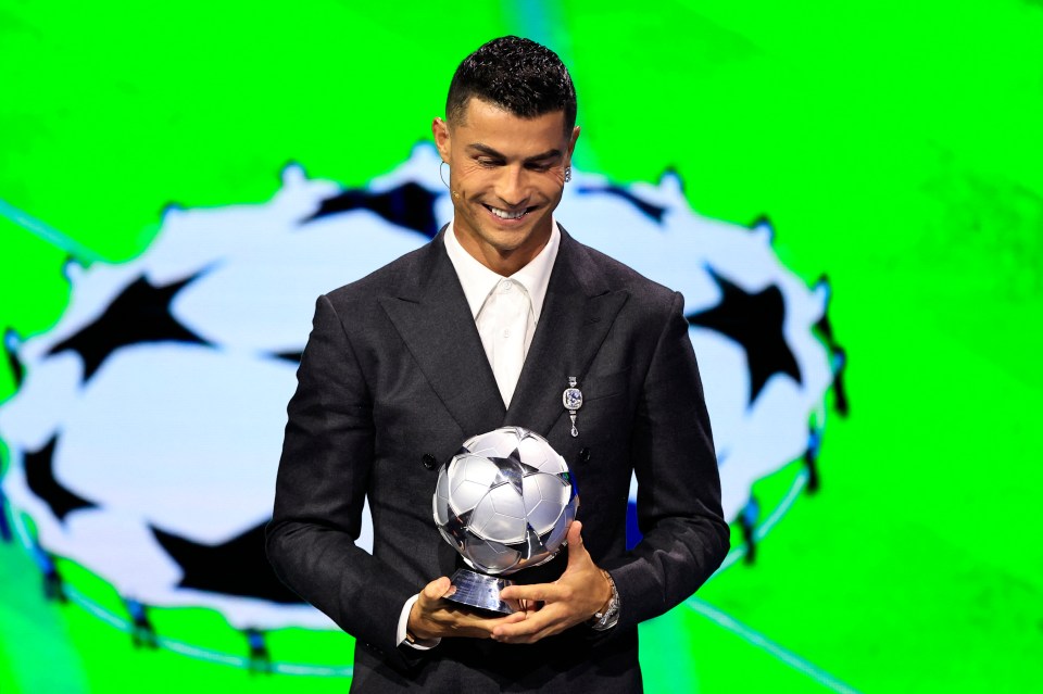 a man in a suit holds a trophy in front of a green background