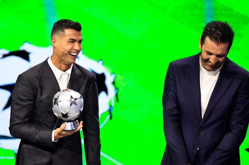 a man in a suit is holding a soccer ball and smiling