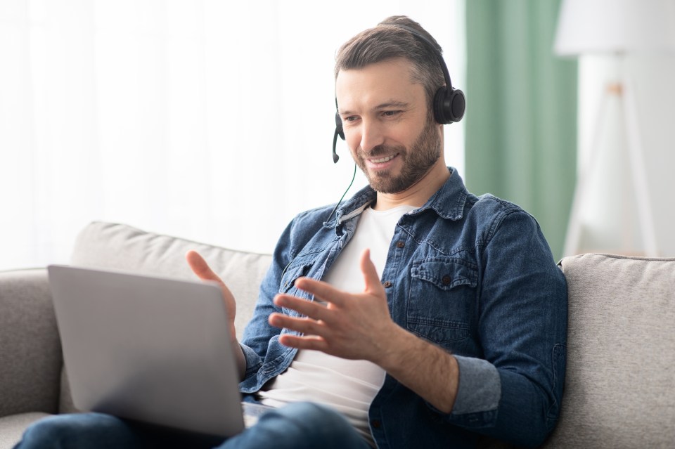 a man wearing headphones is sitting on a couch with a laptop