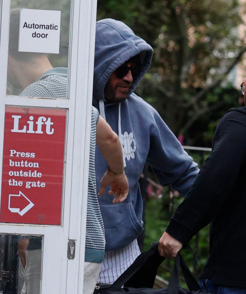 a man in a blue hoodie stands in front of an automatic door