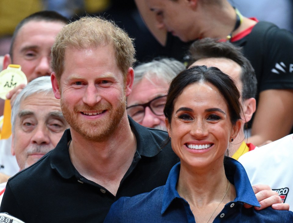 harry and meghan are posing for a picture in front of a crowd