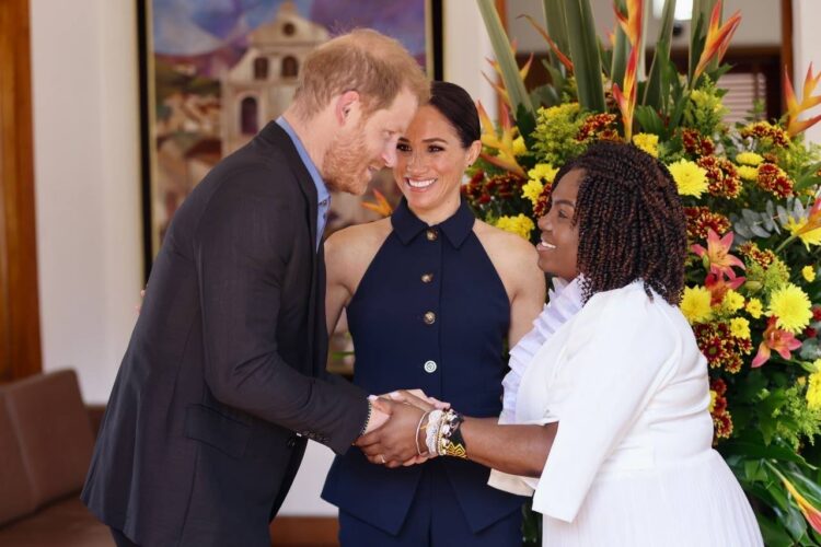 a man and woman are shaking hands in front of flowers