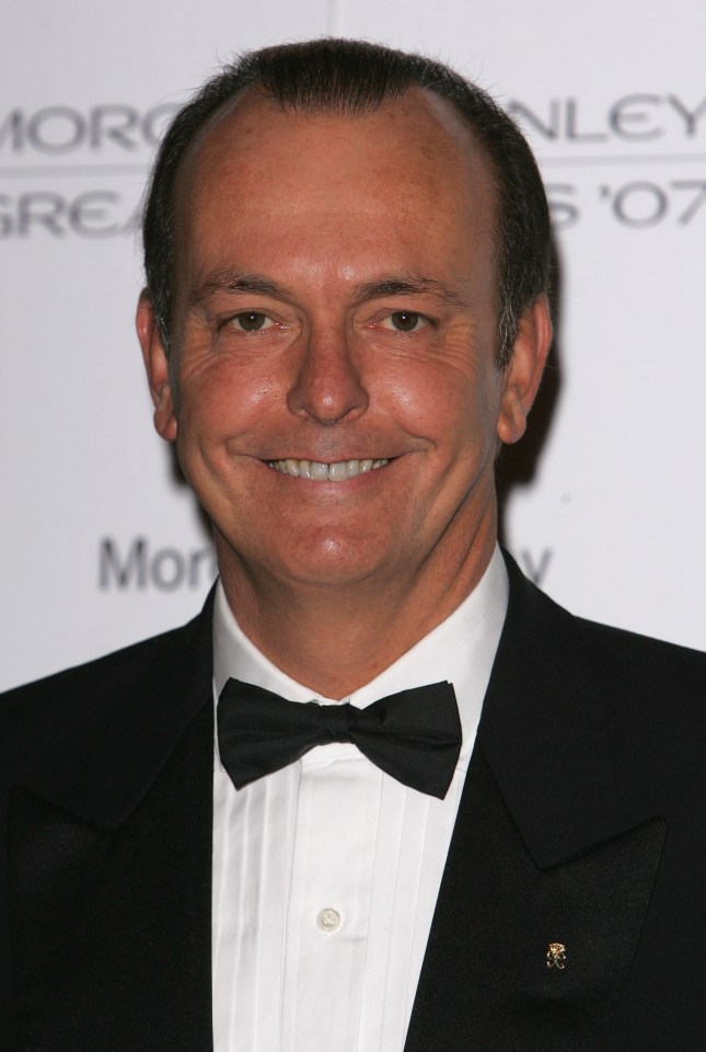 a man in a tuxedo and bow tie smiles in front of a wall that says morley