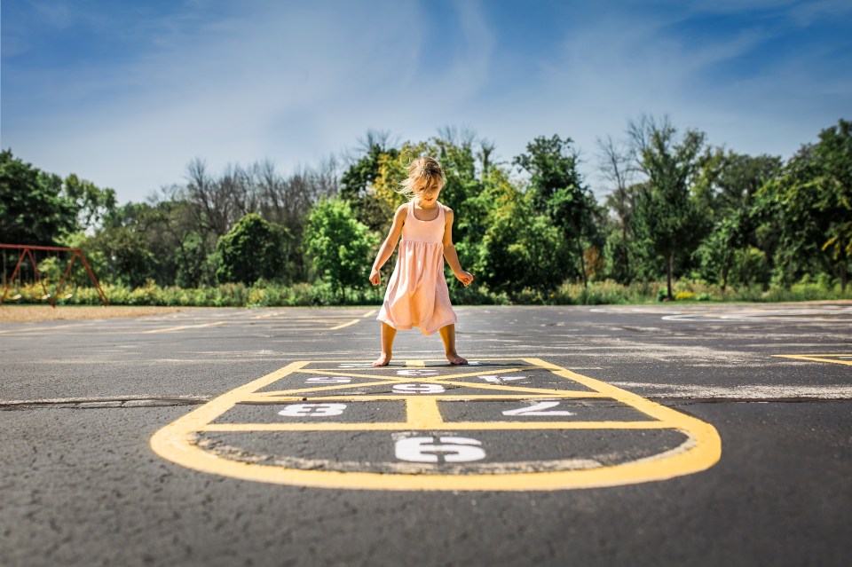 a little girl is playing hopscotch in a parking lot