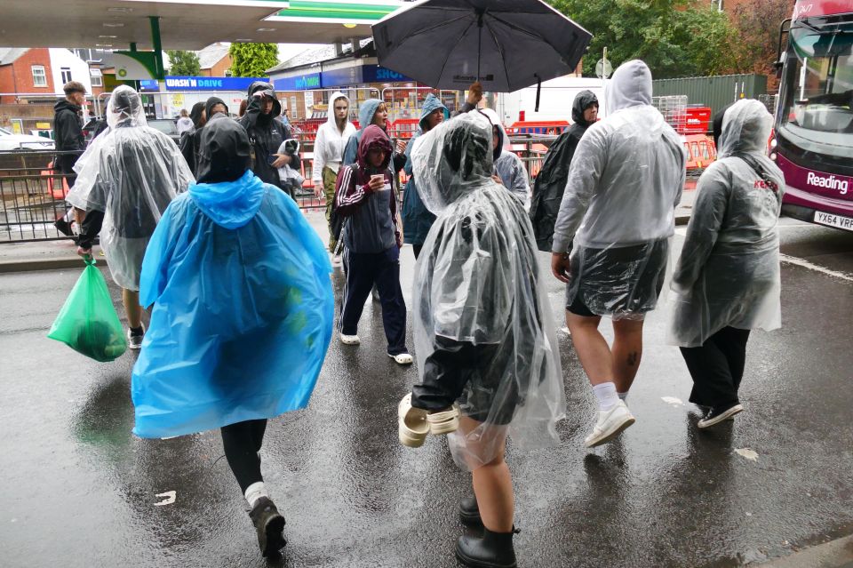 Reading Festival-goers walk through the site during heavy rain