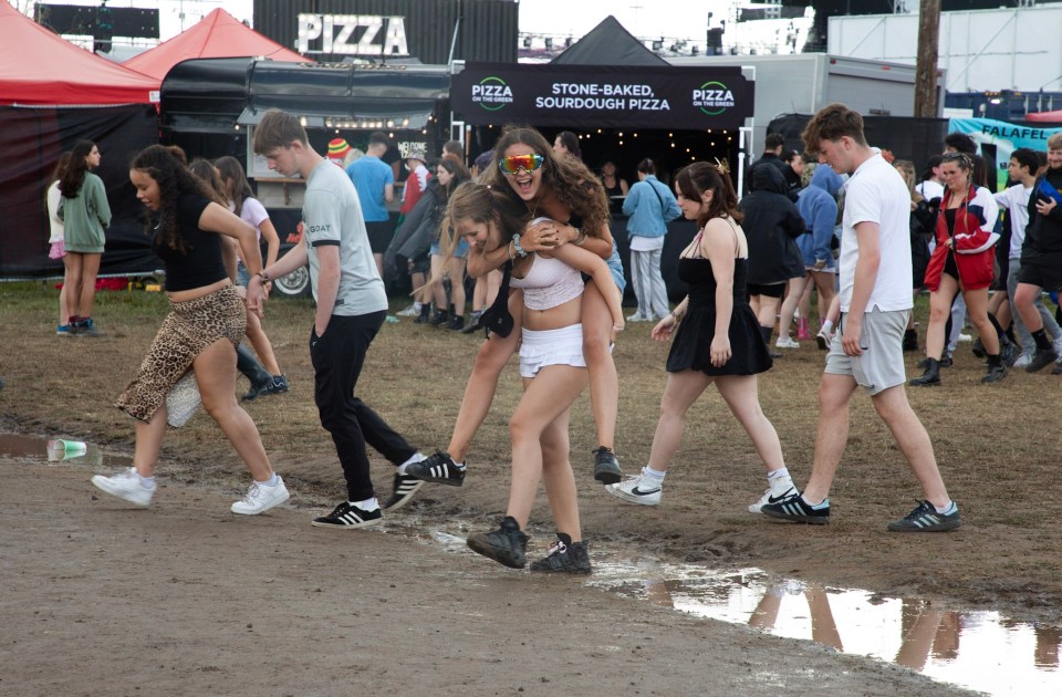 a group of people walking in front of a sign that says pizza