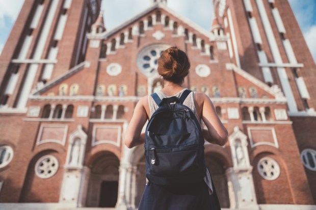 a woman with a backpack stands in front of a church