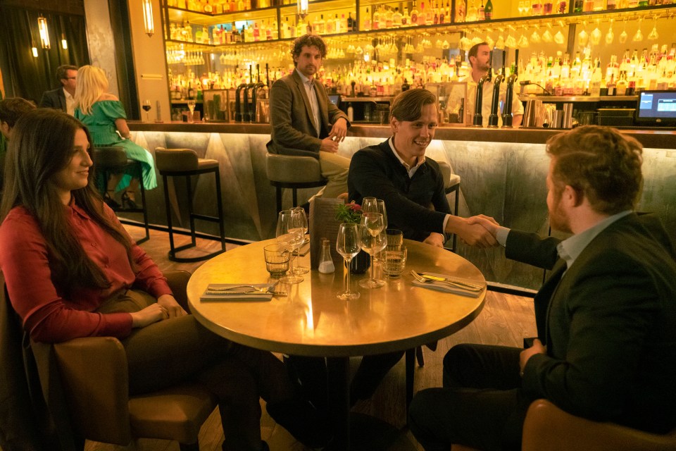 a group of people sitting at a table shaking hands