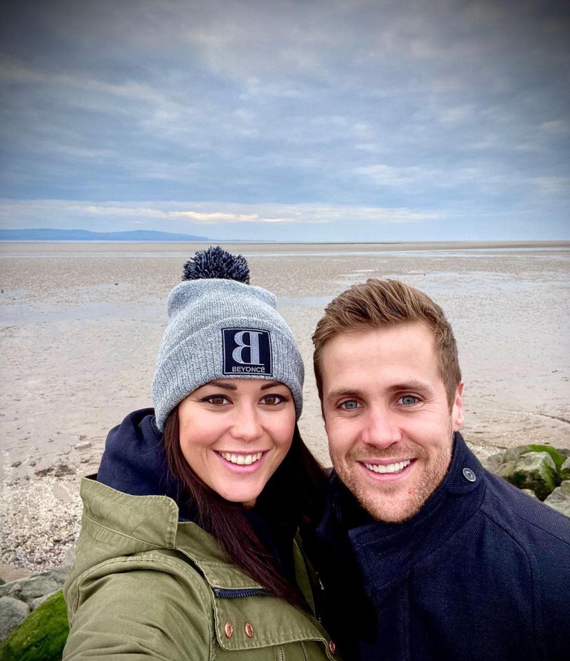 a man and a woman are posing for a picture and the woman is wearing a beanie with the letter b on it