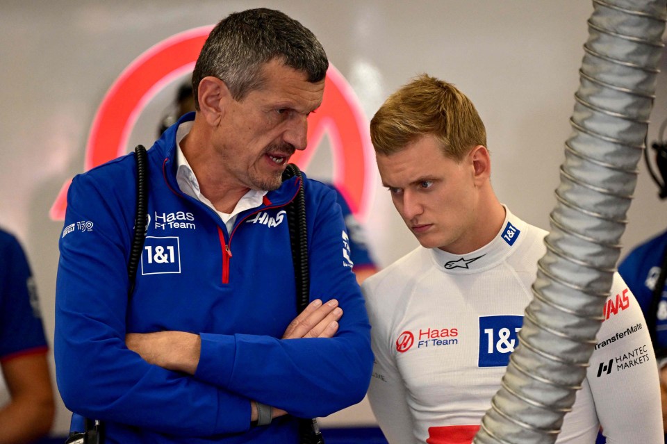 a man in a haas f1 team jacket talks to another man