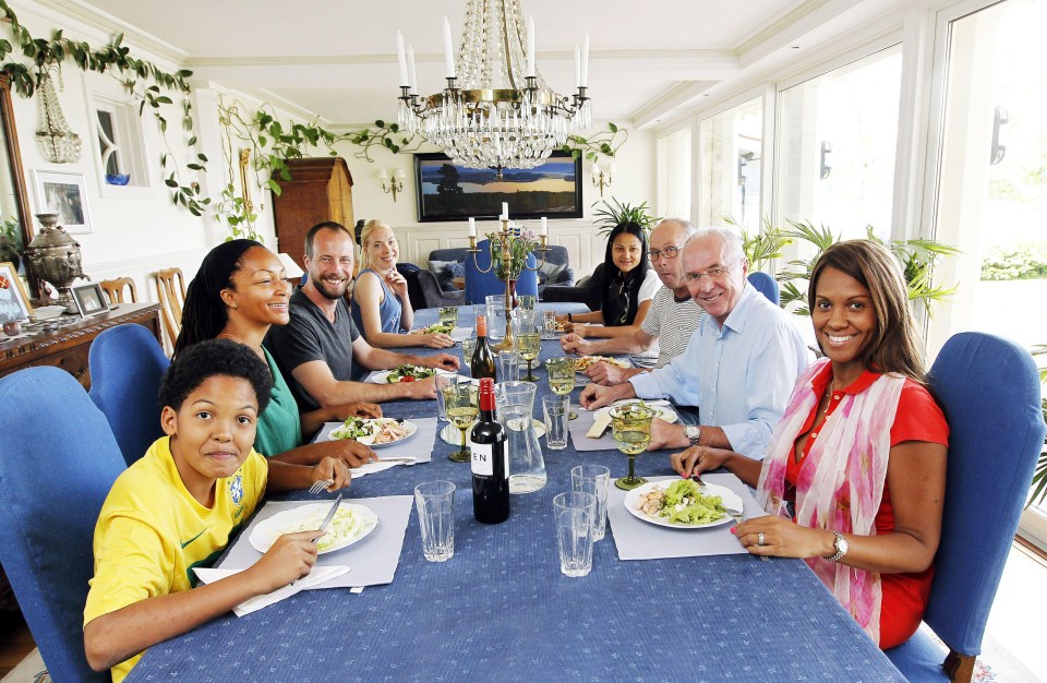 a group of people are sitting at a table with a bottle of gin on it