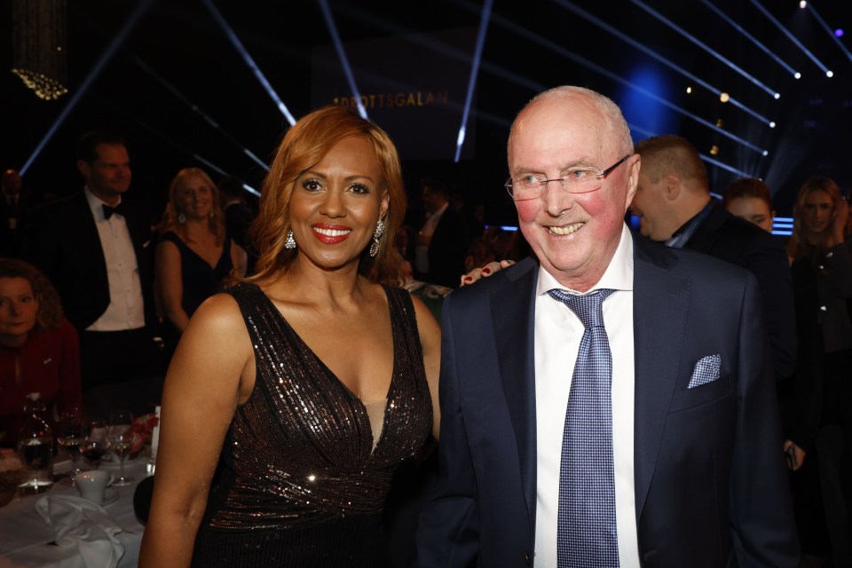 a man and a woman are posing for a picture in front of a sign that says ' sportigala '