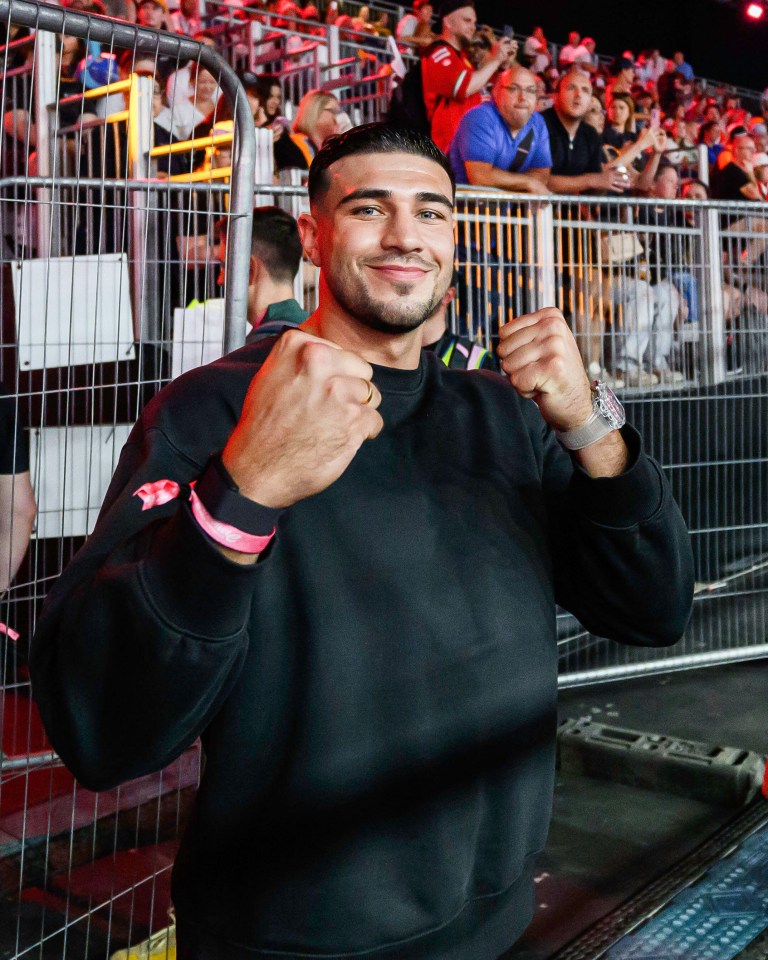 a man in a black sweatshirt with a pink bracelet on his wrist