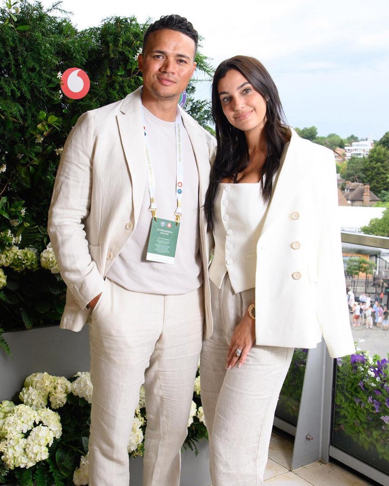 a man and a woman are posing for a picture with a vodafone sign in the background