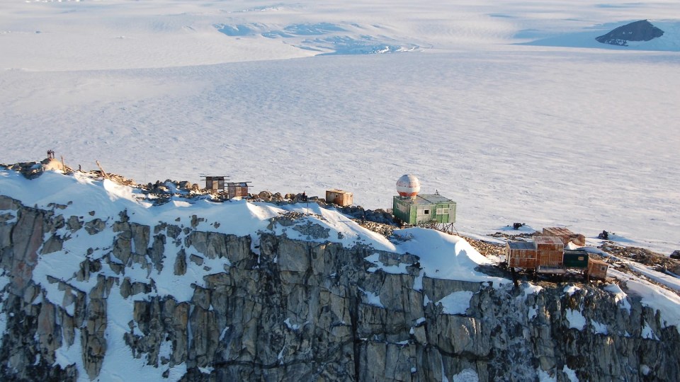 a green building sits on top of a snowy mountain