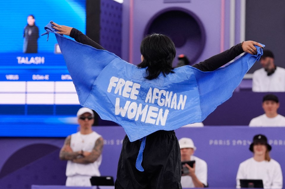 a woman holding a blue cloth that says free afghan women