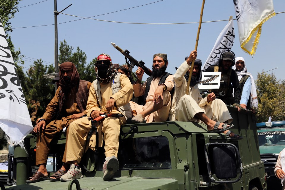 Armed Taliban fighters sit on top of a military truck in Kabul