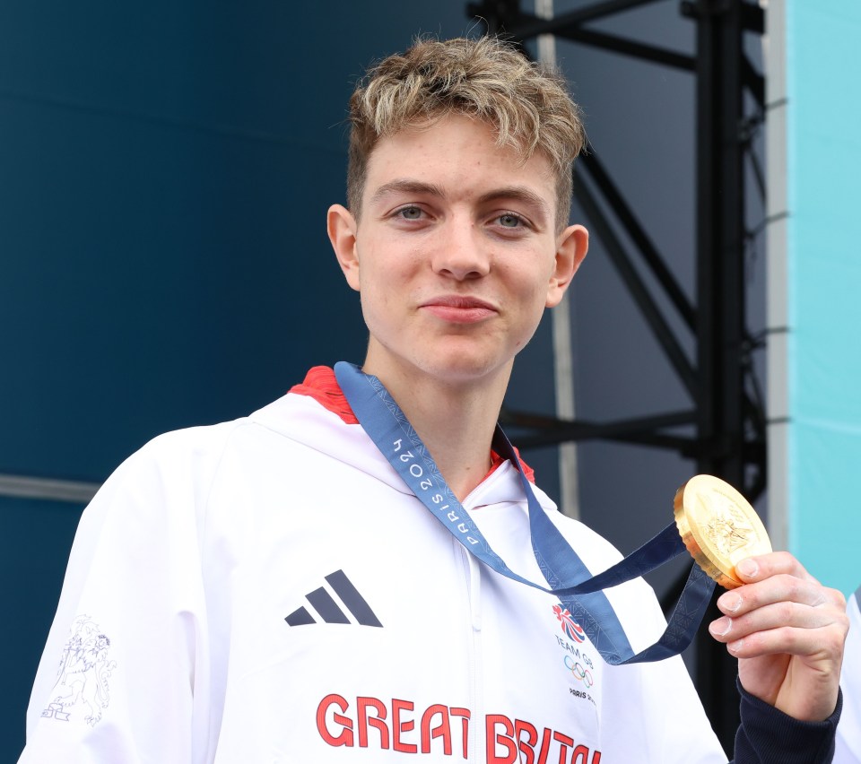 a young man wearing a great britain shirt holds a gold medal