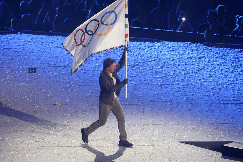 a man holding a flag with the olympic rings on it