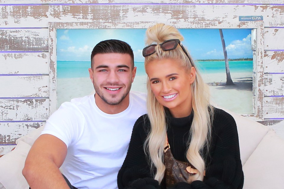 a man and a woman are posing for a picture in front of a beach scene