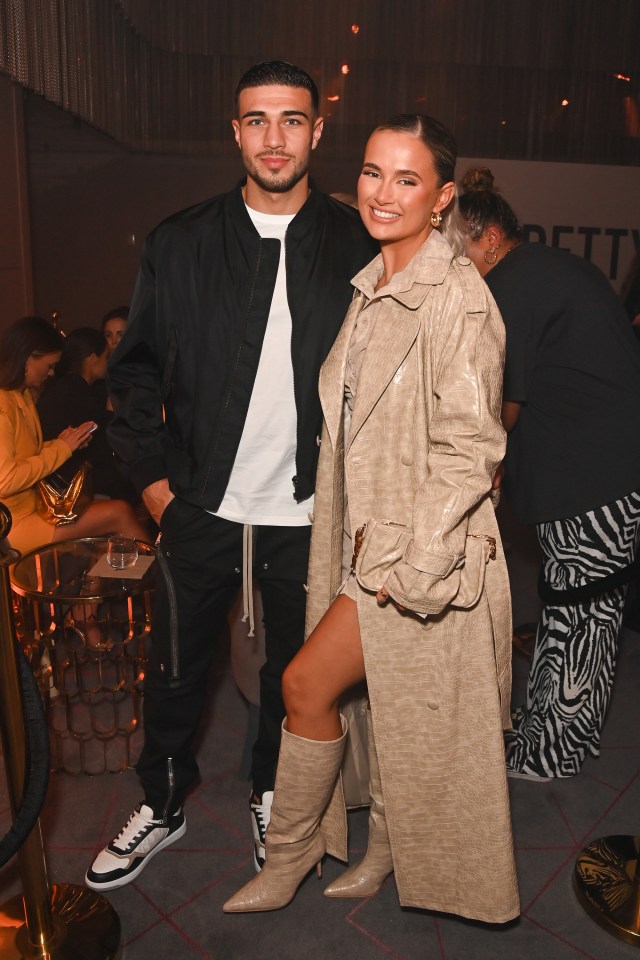 a man and a woman pose for a picture in front of a sign that says pretty