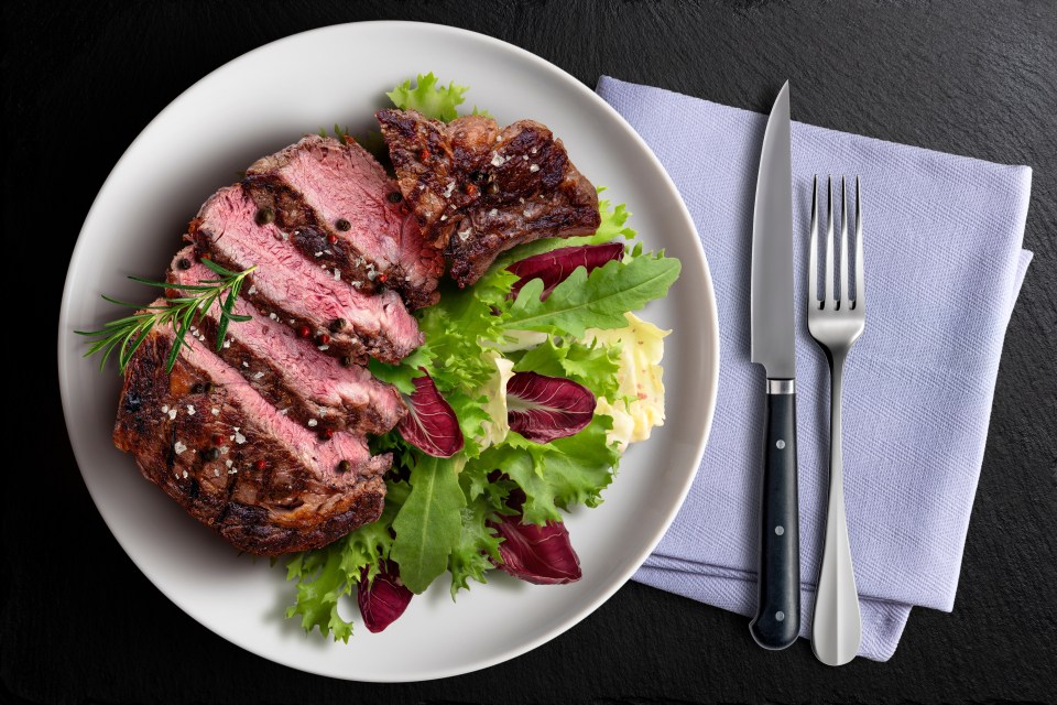 a white plate with a steak and a salad on it