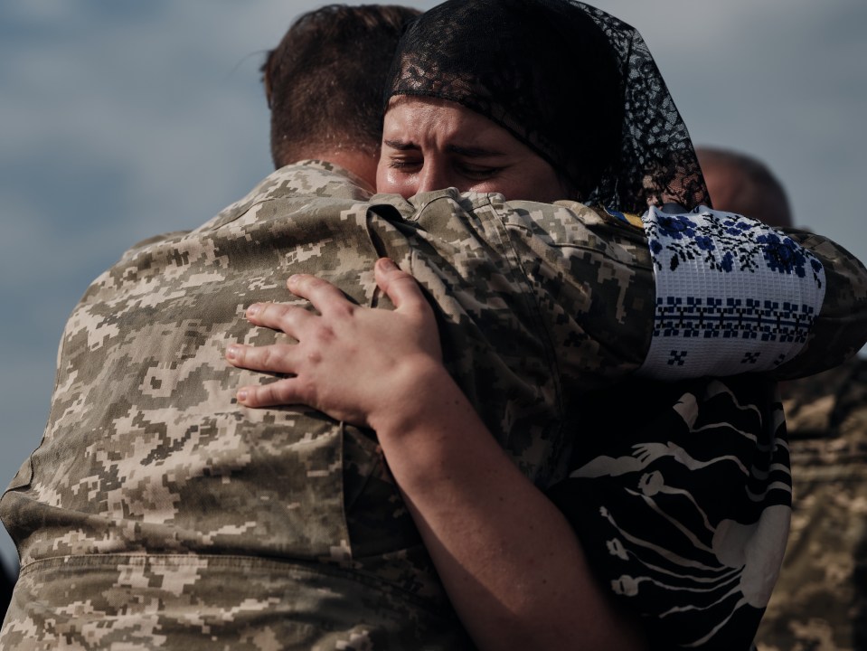 A Ukrainian soldier holds a crying woman at the funeral of Oleksiy