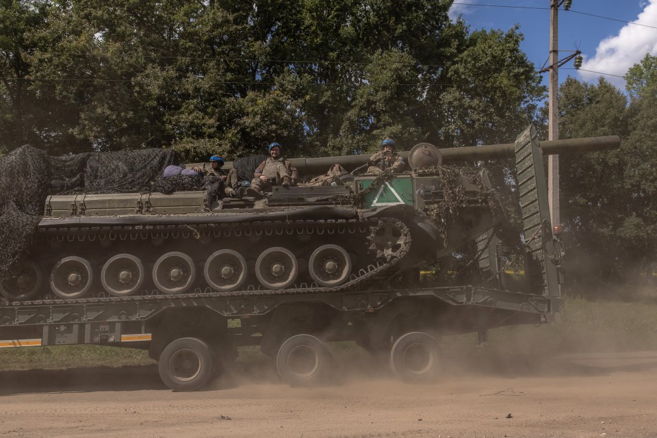 a military vehicle is driving down a dirt road