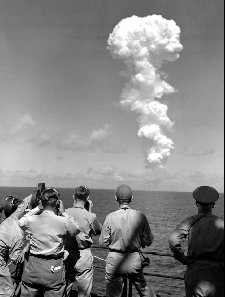 a group of men are looking at a huge cloud in the sky