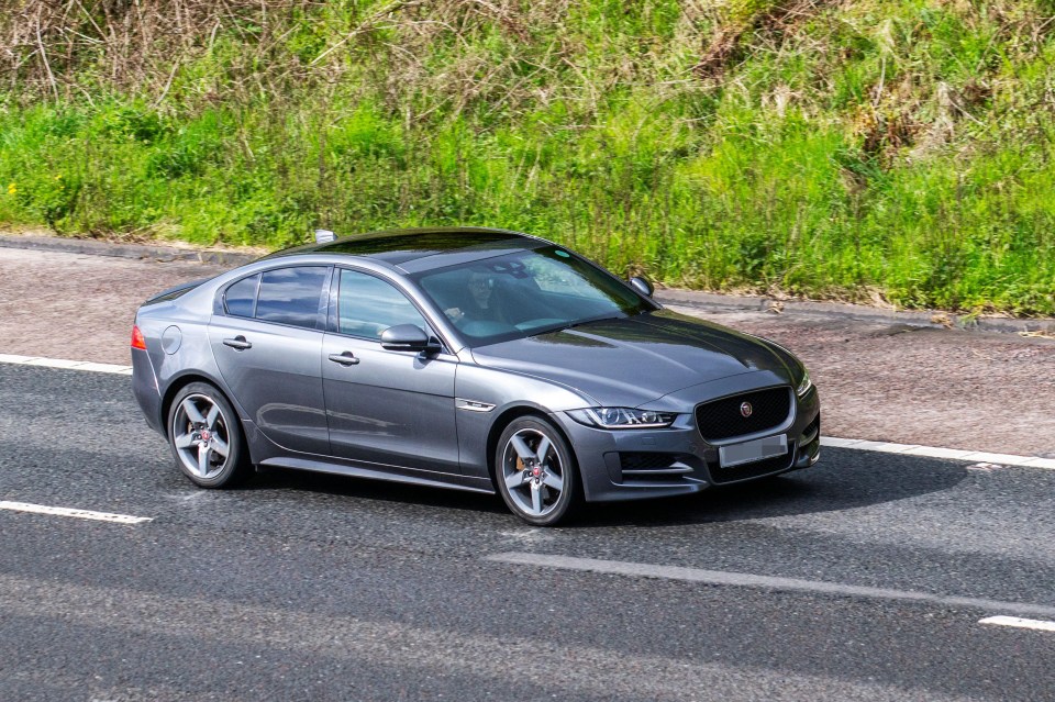 a gray jaguar is driving down the road