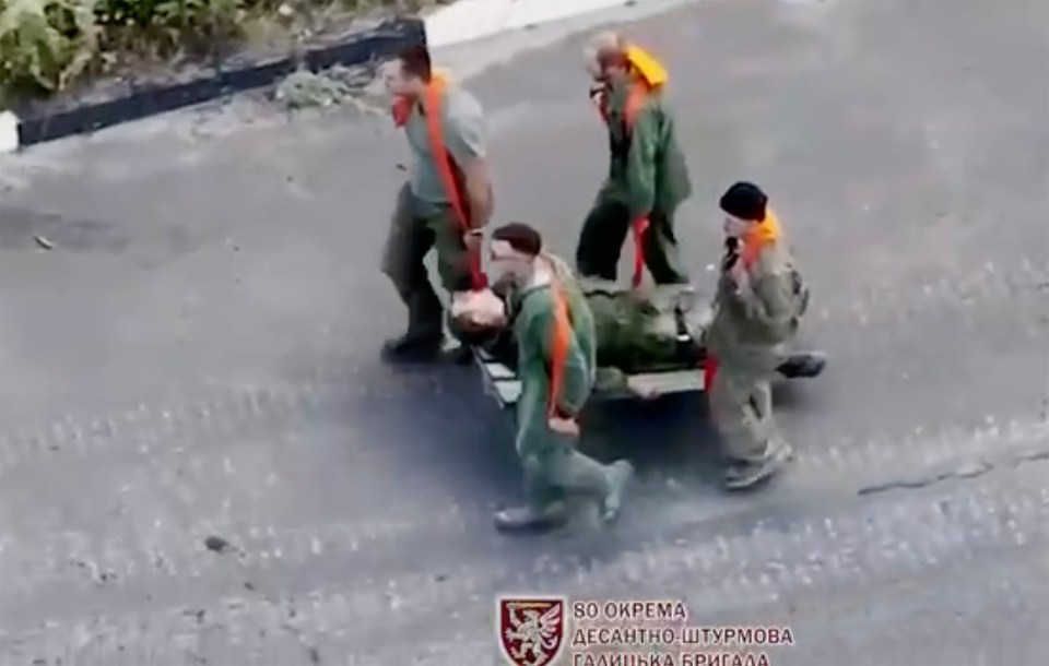 Troops move one injured man in the clip