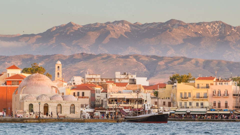 a boat is docked in front of a city with mountains in the background