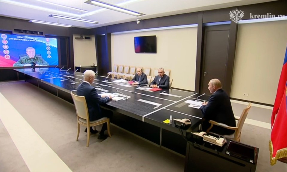 four men sit at a long table in front of a screen that says kremlin.ru