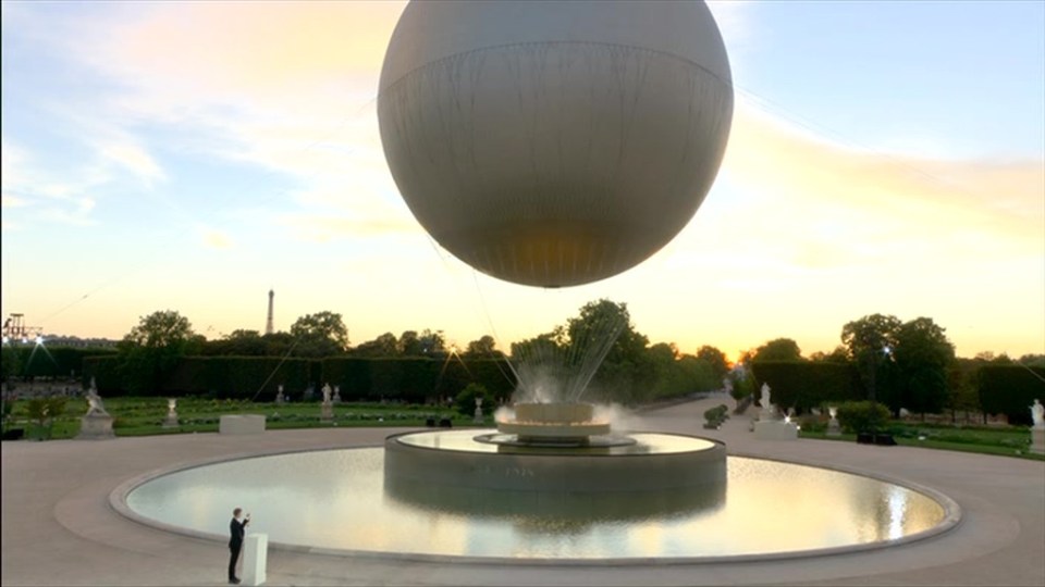 a large white ball is floating over a fountain