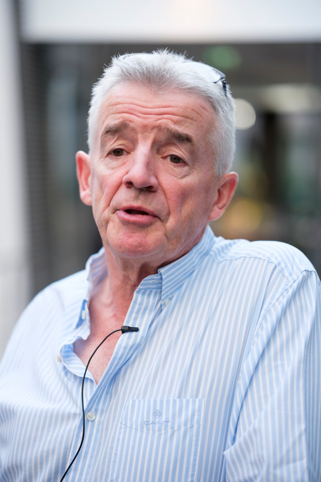 a man wearing a blue and white striped shirt has a microphone attached to his neck