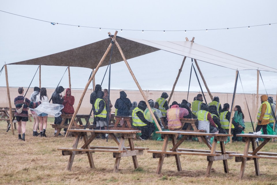 a group of people sitting at picnic tables under a canopy